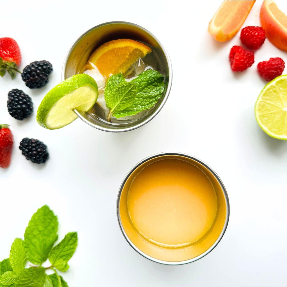 Toddler stainless steel drink cups with colourful silicone sleeves, filled with juice.