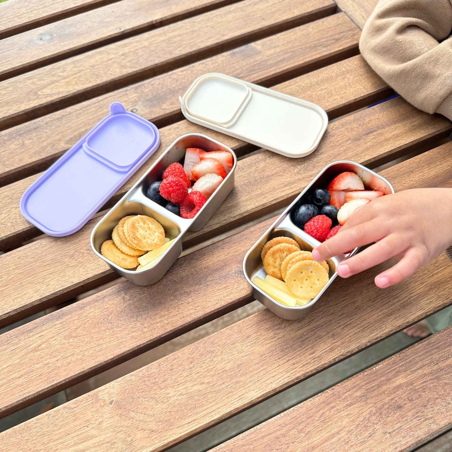 Greenvyne Kids snack box stainless steel with leak resistant purple silicone sleeve, filled with fruits and snacks.