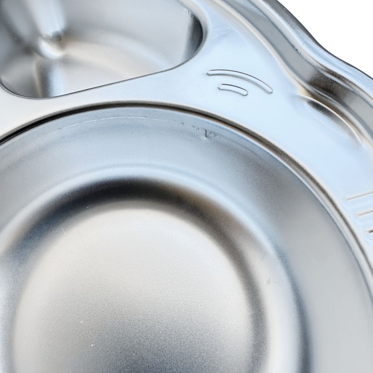 Close-up view of imperfections on a kid's stainless steel seconds car-shaped plate with suction.