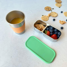 kids and adults stainless steel cup 350ml with silicone band for easy grip. paired with greenvyne stainless steel 2 compartment snack box with fruits on a table.