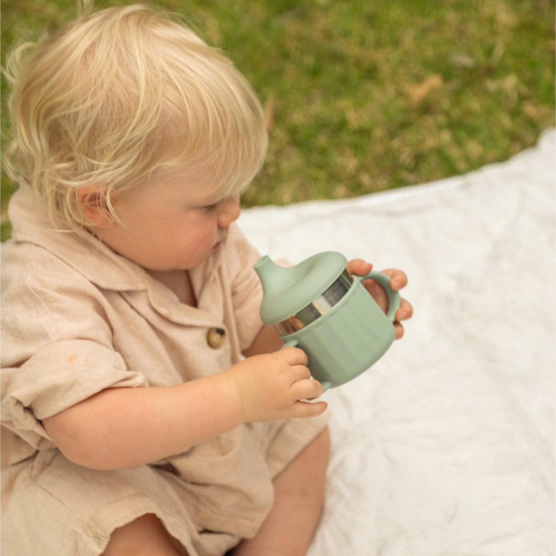 Toddler using Greenvyne 3-in-1 sippy cup in Sage colour, showing its leak resistant sippy spout and soft silicone handle.