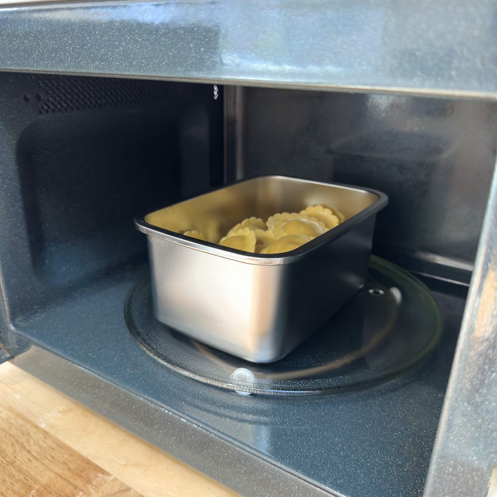 Stainless steel 304 grade food storage container in a microwave with pasta reheating. BPA, phthalates and microplastic free. Greenvyne.